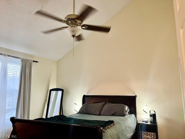 bedroom with lofted ceiling, ceiling fan, and a textured ceiling