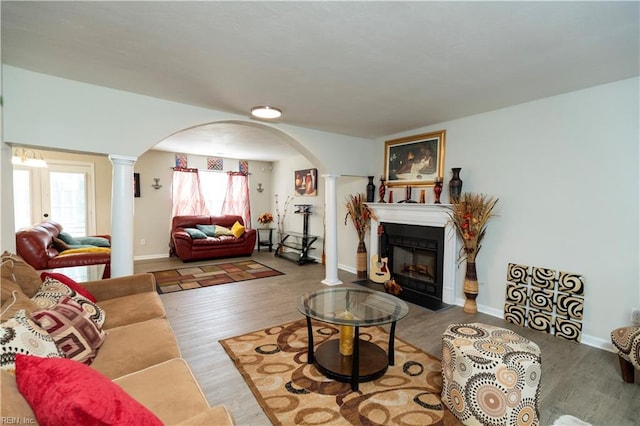 living room featuring arched walkways, decorative columns, and wood finished floors