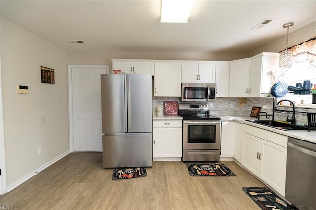 kitchen featuring visible vents, stainless steel appliances, a sink, and light countertops