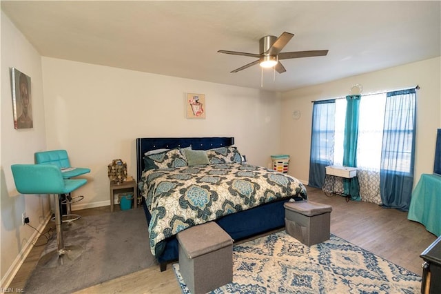 bedroom featuring ceiling fan, baseboards, and wood finished floors