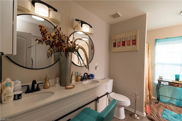 full bath with toilet, baseboards, visible vents, and a sink