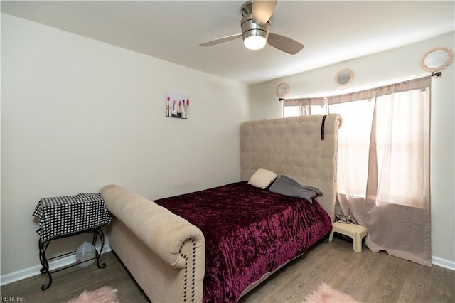 bedroom with ceiling fan, wood finished floors, and baseboards