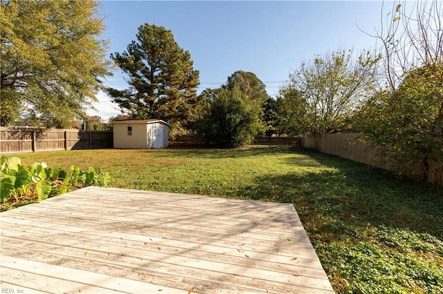 wooden terrace featuring an outbuilding, a yard, a storage shed, and a fenced backyard