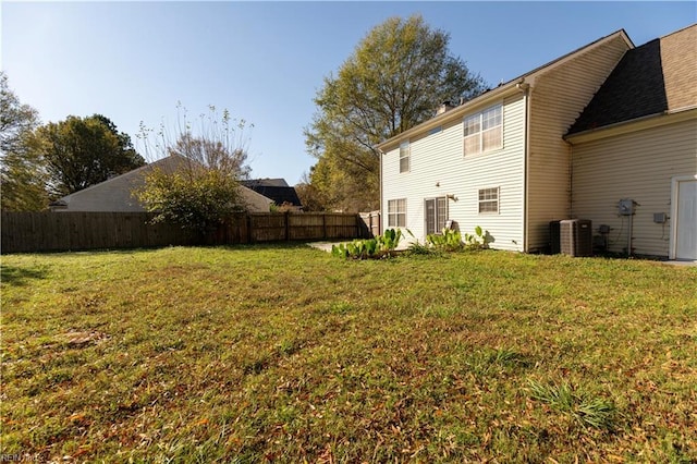 rear view of house featuring a yard, central AC, and fence