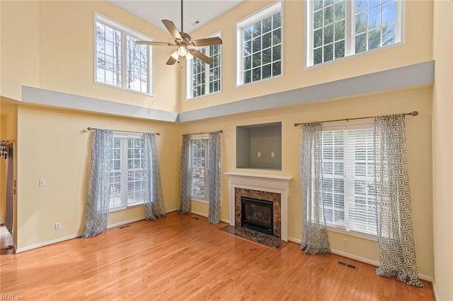 unfurnished living room featuring baseboards, visible vents, ceiling fan, wood finished floors, and a fireplace