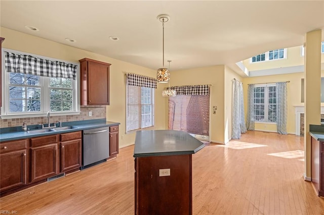 kitchen featuring dark countertops, light wood finished floors, a sink, and stainless steel dishwasher