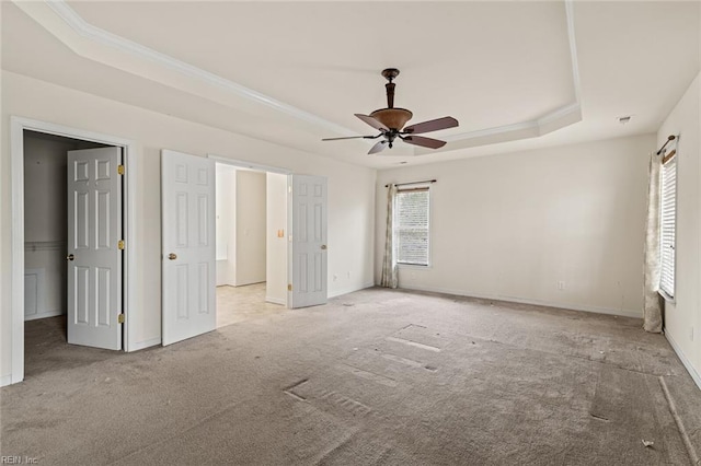 unfurnished bedroom with carpet, multiple windows, a raised ceiling, and crown molding