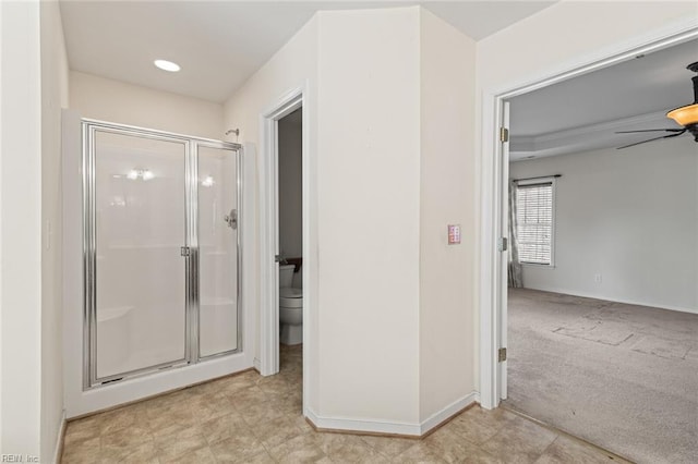 bathroom with baseboards, a stall shower, toilet, and a ceiling fan