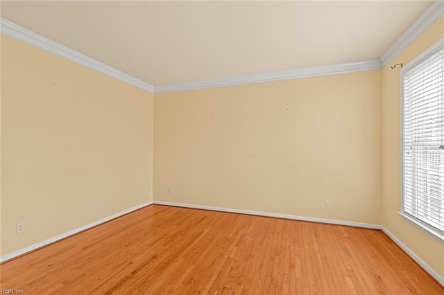 empty room with light wood-style flooring, baseboards, and crown molding