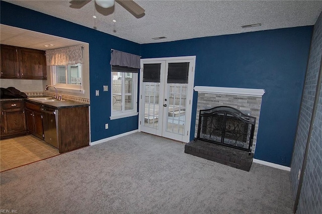 unfurnished living room with light colored carpet, a sink, visible vents, and a fireplace