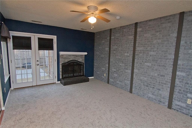 unfurnished living room with french doors, a fireplace, visible vents, carpet flooring, and a textured ceiling