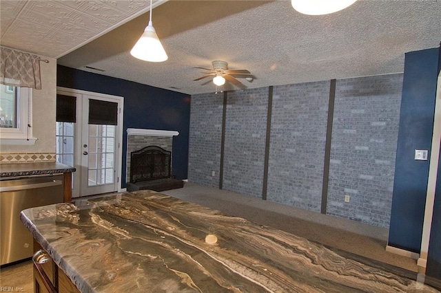 bedroom featuring a fireplace with raised hearth, brick wall, access to exterior, a textured ceiling, and french doors