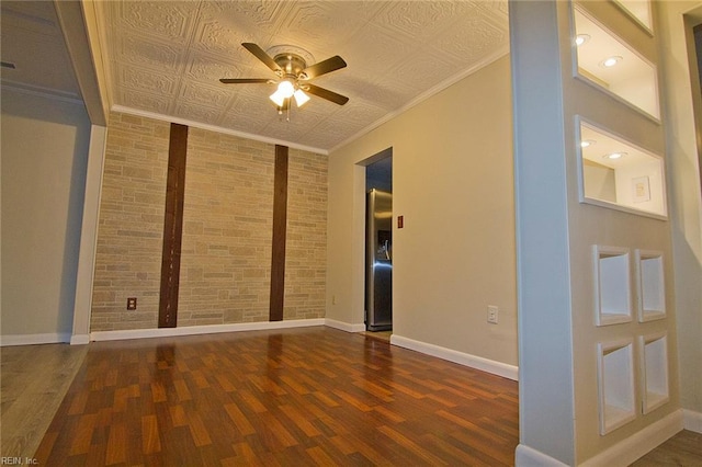 empty room featuring baseboards, a ceiling fan, brick wall, wood finished floors, and crown molding