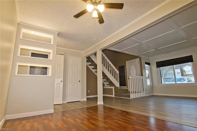 foyer entrance with wood finished floors, a ceiling fan, baseboards, stairs, and an ornate ceiling