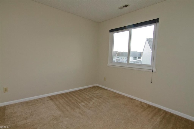 carpeted empty room with visible vents and baseboards