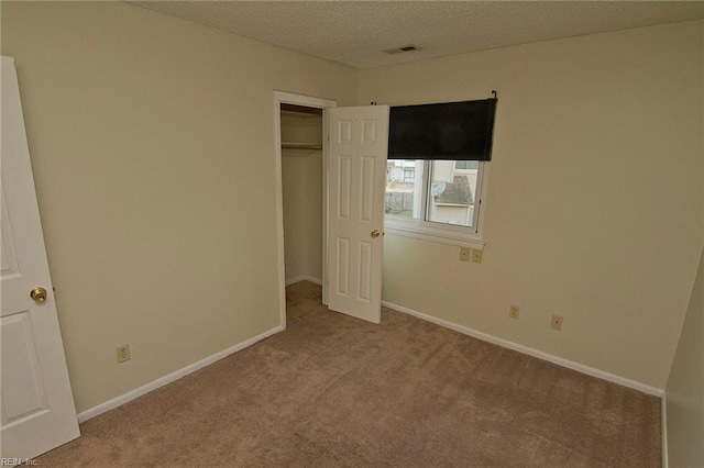 unfurnished bedroom with carpet floors, a closet, visible vents, a textured ceiling, and baseboards