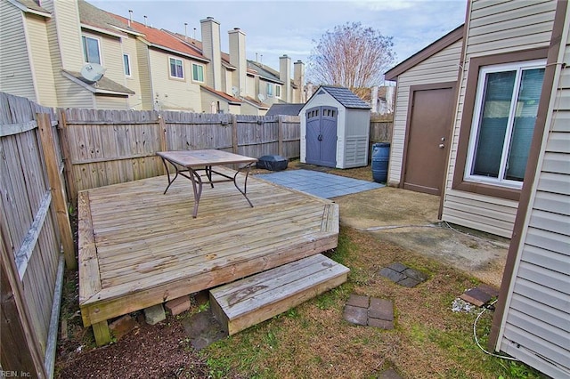 wooden deck featuring a shed, a fenced backyard, and an outbuilding