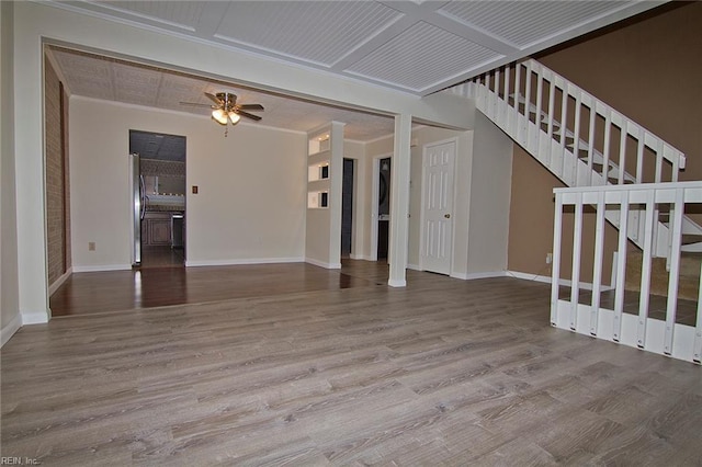 unfurnished living room featuring baseboards, coffered ceiling, ceiling fan, stairway, and wood finished floors