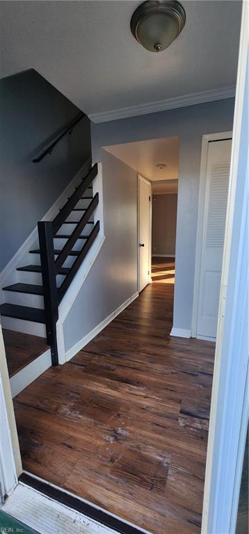 staircase featuring baseboards, wood finished floors, and crown molding