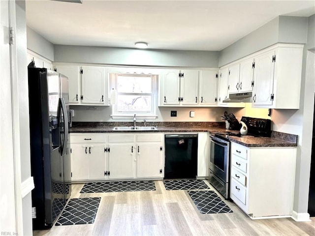 kitchen with dark countertops, white cabinets, a sink, under cabinet range hood, and black appliances