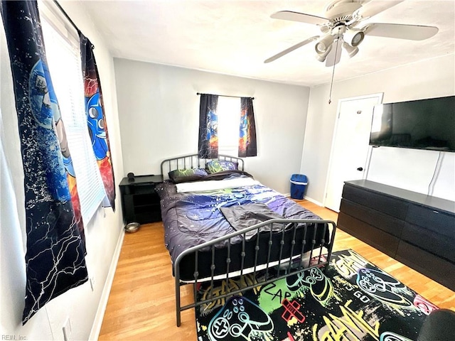 bedroom with multiple windows, ceiling fan, baseboards, and wood finished floors