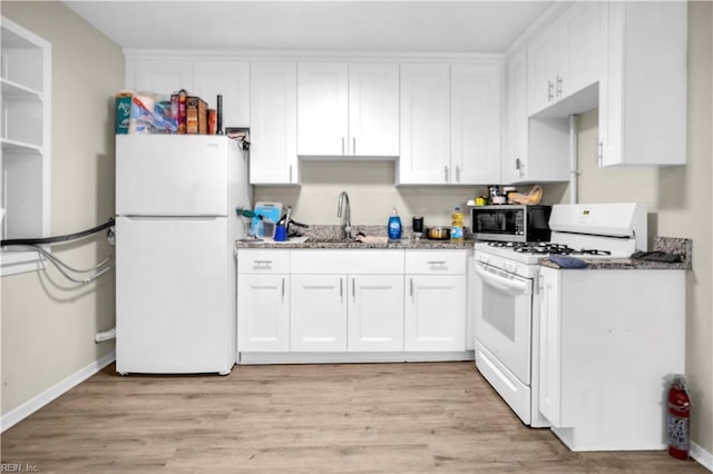 kitchen featuring white appliances, light wood finished floors, stone counters, white cabinetry, and a sink