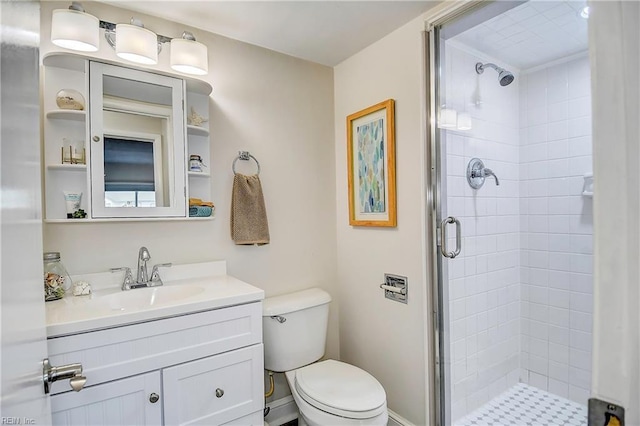 bathroom with toilet, a shower stall, baseboards, and vanity