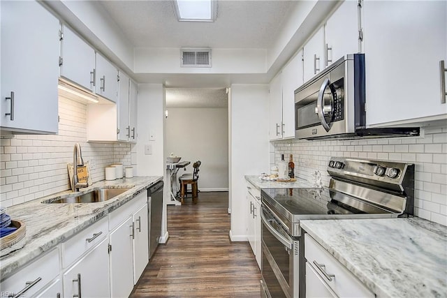 kitchen with visible vents, white cabinets, dark wood-type flooring, stainless steel appliances, and a sink