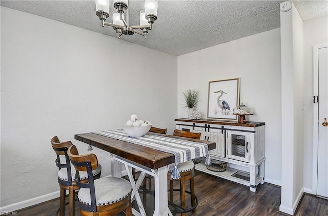 dining space with a notable chandelier, a textured ceiling, baseboards, and wood finished floors