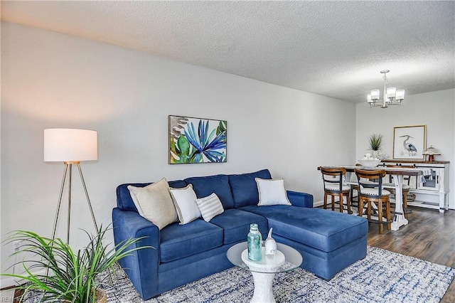 living area featuring a textured ceiling, dark wood-type flooring, and an inviting chandelier