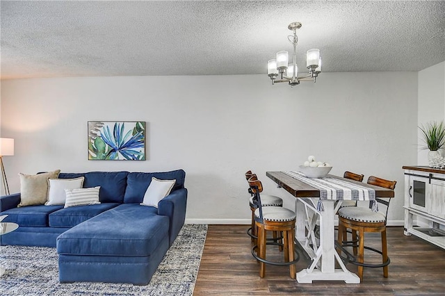 dining area featuring a chandelier, a textured ceiling, baseboards, and wood finished floors