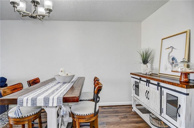 dining space featuring dark wood-style floors, a textured ceiling, baseboards, and a notable chandelier