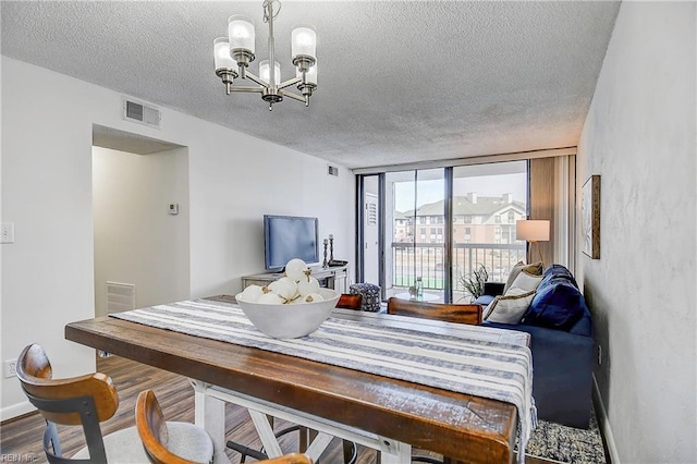 interior space featuring a chandelier, a textured ceiling, wood finished floors, visible vents, and expansive windows