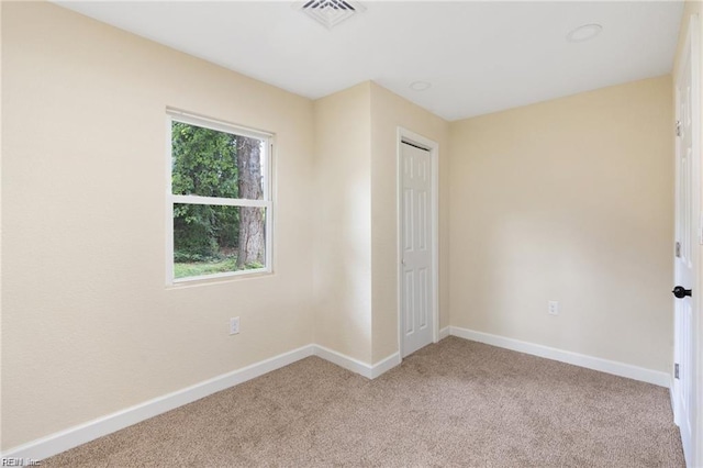 unfurnished bedroom featuring baseboards, visible vents, and light colored carpet