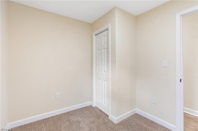 spare room with light colored carpet and baseboards