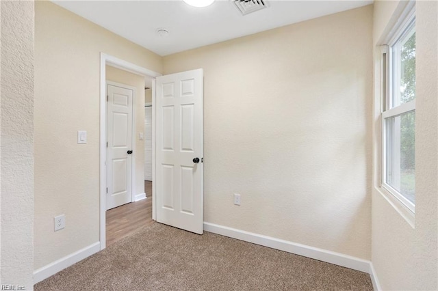 empty room with baseboards, visible vents, and carpet flooring