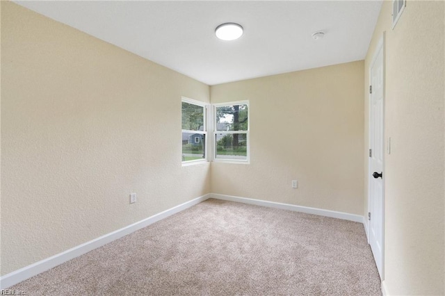 carpeted empty room featuring baseboards