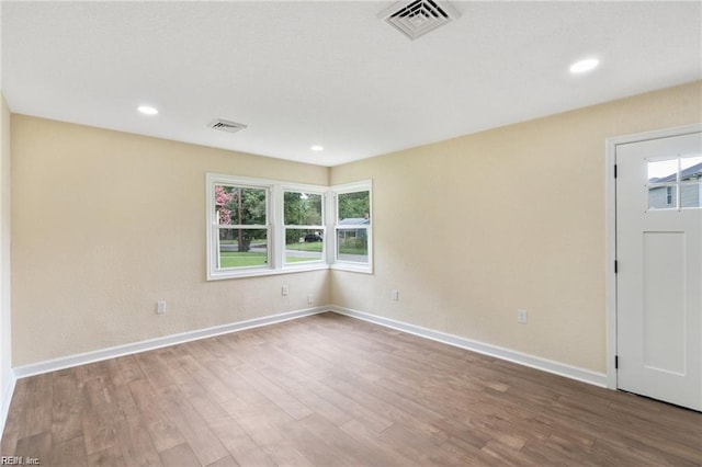 unfurnished room featuring recessed lighting, visible vents, baseboards, and wood finished floors