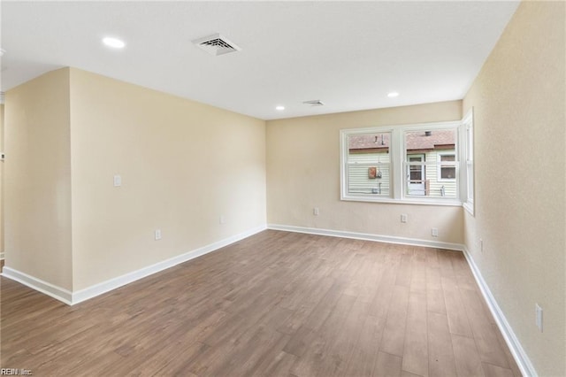 empty room featuring recessed lighting, visible vents, baseboards, and wood finished floors