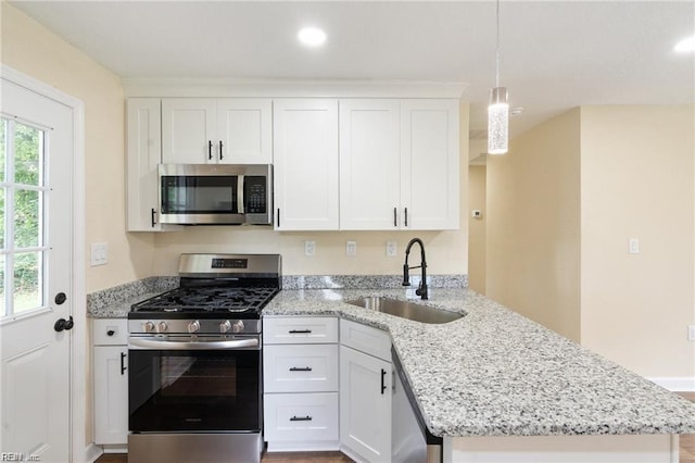 kitchen featuring a peninsula, white cabinetry, appliances with stainless steel finishes, and a sink