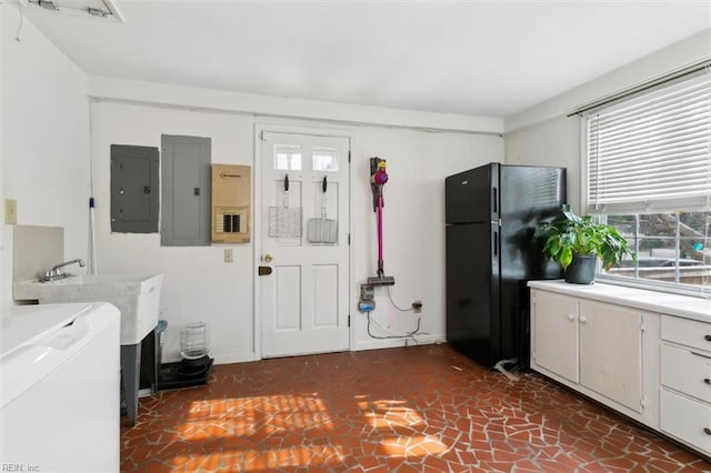 interior space featuring washing machine and clothes dryer, electric panel, light countertops, and freestanding refrigerator