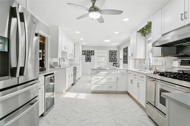 kitchen featuring wine cooler, marble finish floor, appliances with stainless steel finishes, a sink, and under cabinet range hood