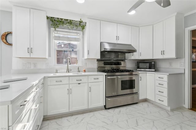 kitchen with under cabinet range hood, a sink, marble finish floor, appliances with stainless steel finishes, and light countertops