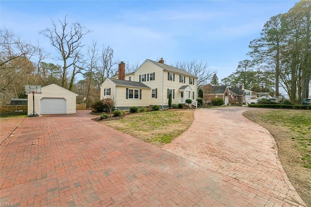 view of front of home with an outbuilding, decorative driveway, a chimney, and a garage