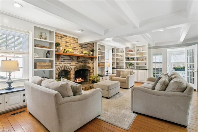 living area with light wood-style floors, a brick fireplace, visible vents, and a healthy amount of sunlight