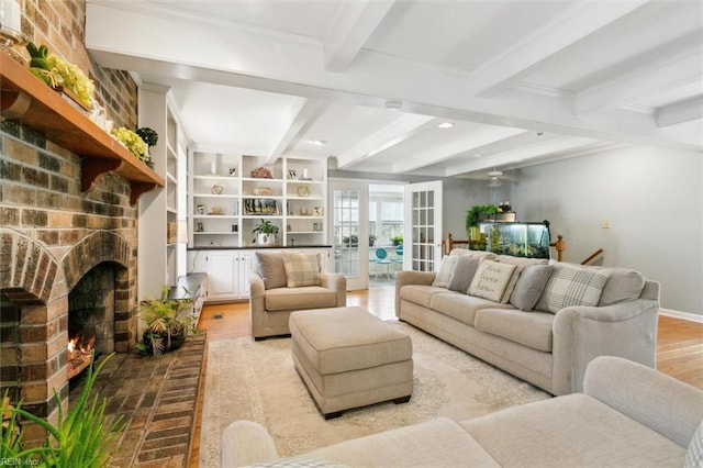 living area featuring baseboards, beamed ceiling, wood finished floors, crown molding, and a fireplace