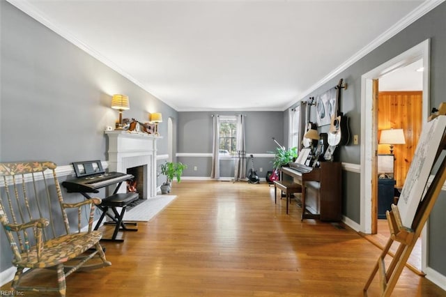 living area featuring a warm lit fireplace, ornamental molding, and wood finished floors