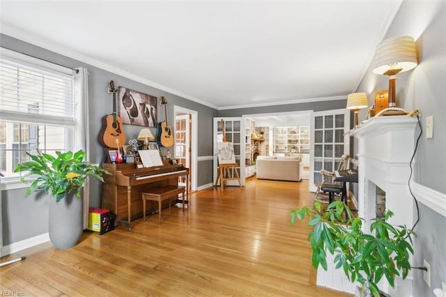 living area featuring ornamental molding, a fireplace, light wood-style flooring, and baseboards