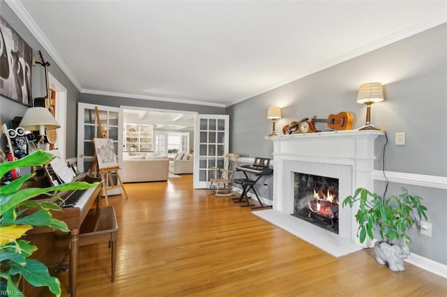 living room with a fireplace with flush hearth, ornamental molding, and wood finished floors