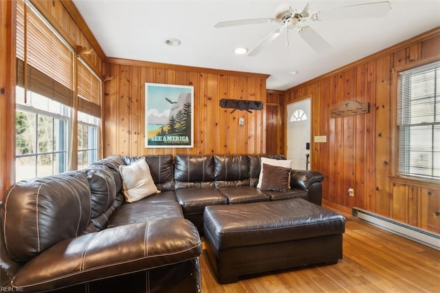 living area with ornamental molding, wood walls, and baseboard heating